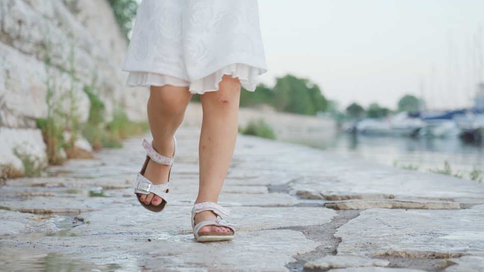 Little girl dressed in white runs on the stones