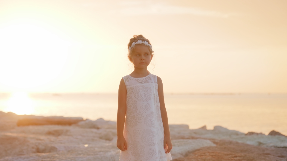 Bambina in piedi al tramonto sulla laguna