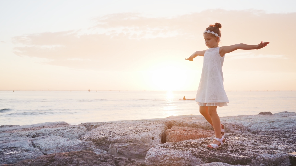 Little girl walks on the stones at the sea