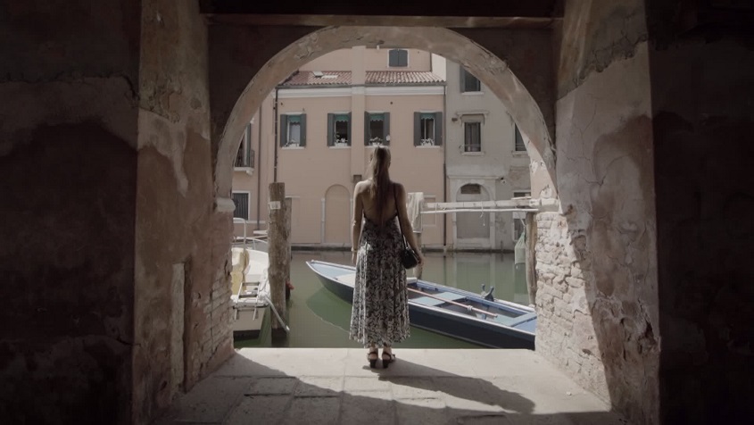 Woman looks at canal under arcades in Venice