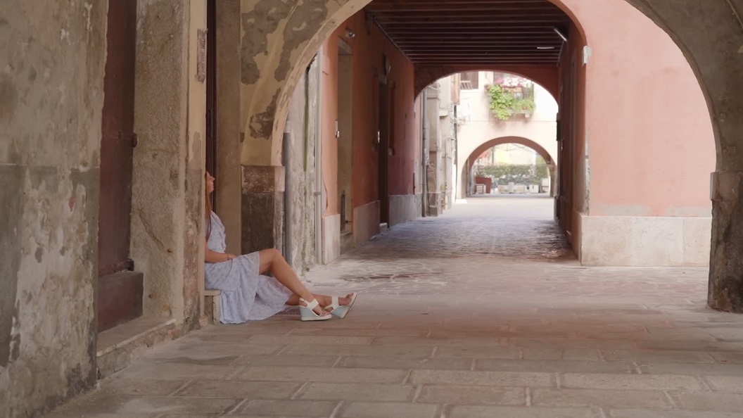 Venetian Ambiance: Woman Sitting in a Venetian Street in Front of a House Door