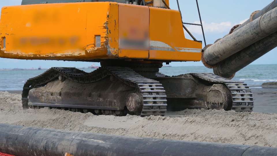 l’escavatore cingolato trasporta il carico sulla spiaggia