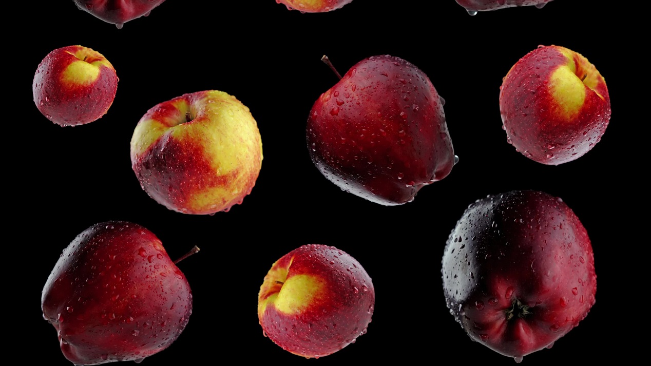 Ripe apples fall from above on a black background