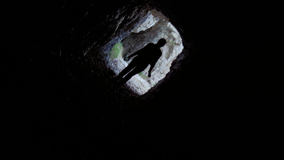 Girl enters a dark cave in the rocks