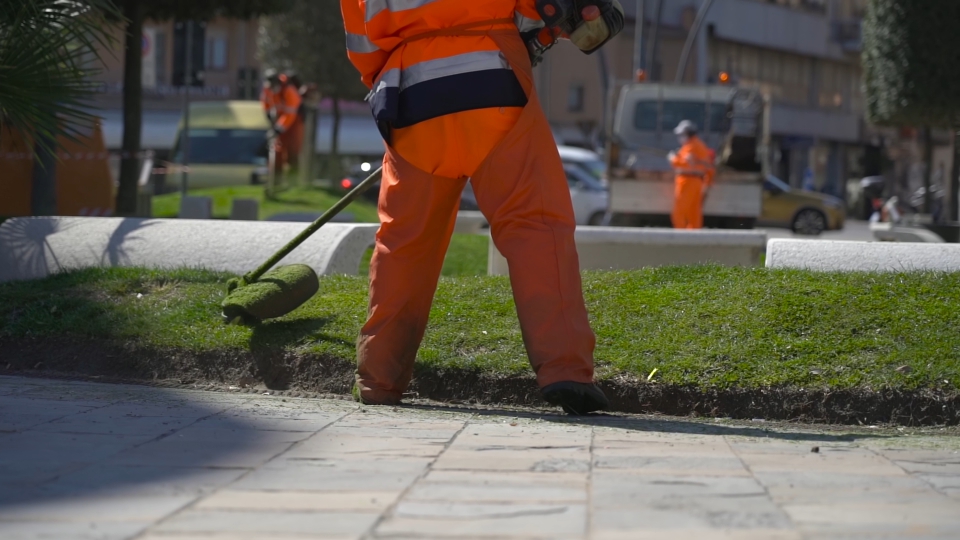 Lawnmower cuts grass in the city