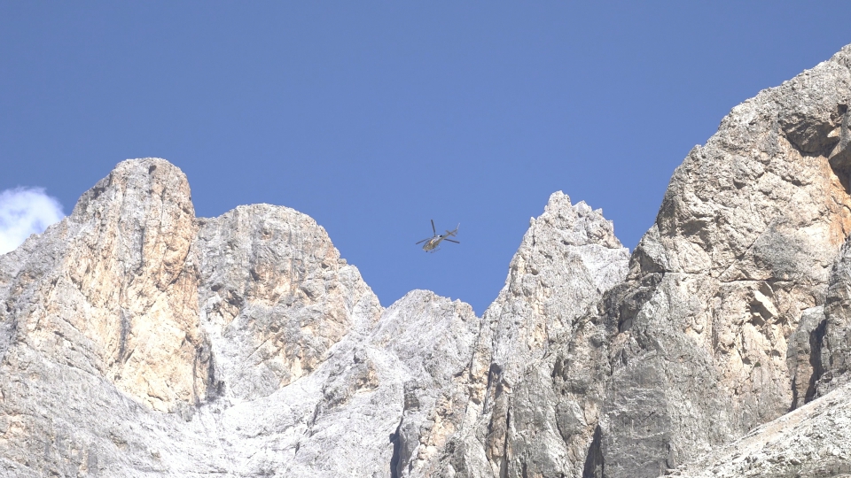 Helicopter flies in front of high mountains