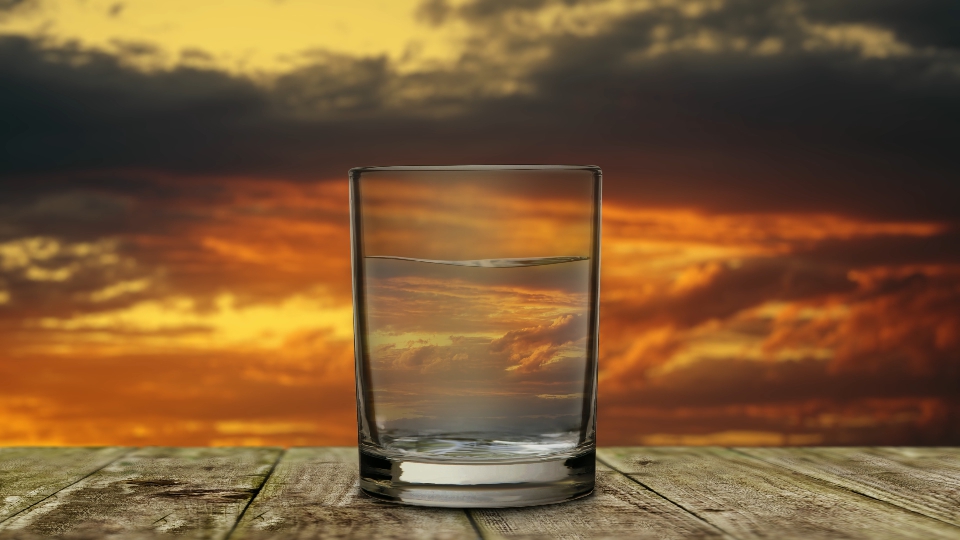 Bicchiere con acqua con cielo al tramonto