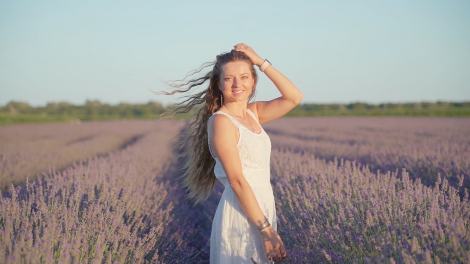 Donna con cappelli sciolti sul campo di lavanda