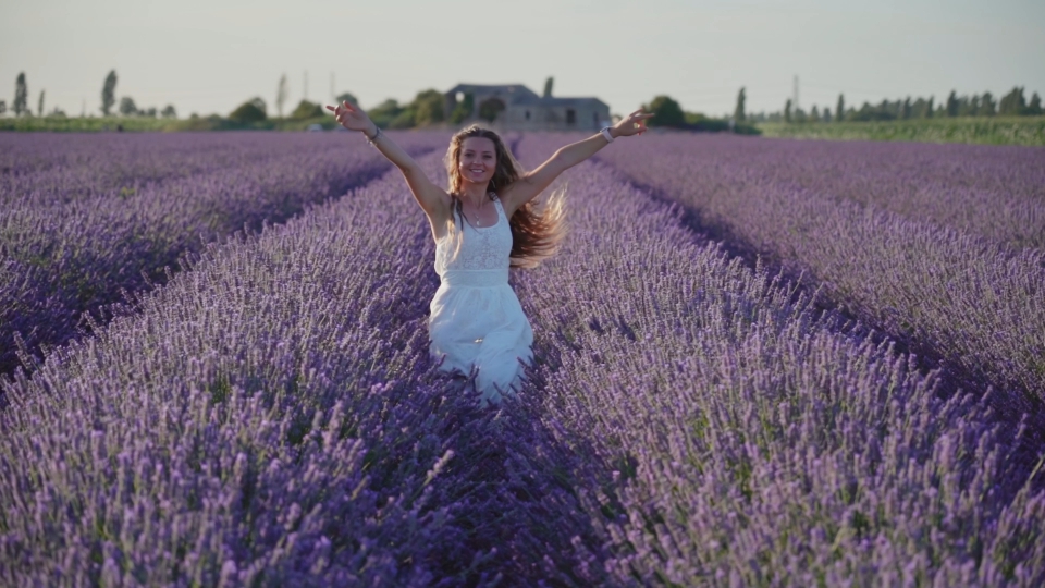 Donna sorridente salta tra le piante di lavanda viola