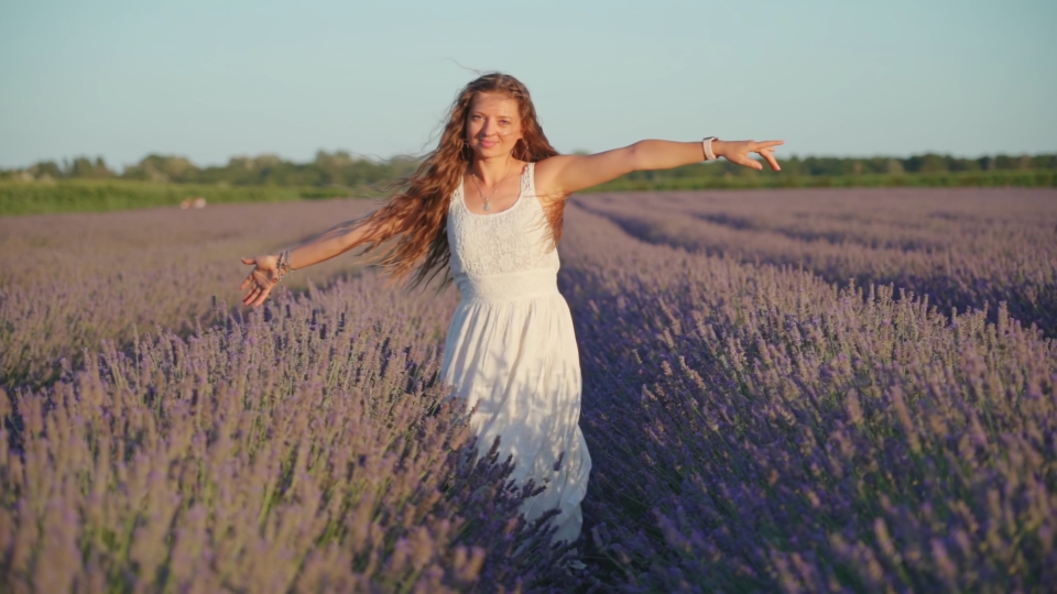 Donna vestita in abito bianco con cappelli sciolti tra la natura