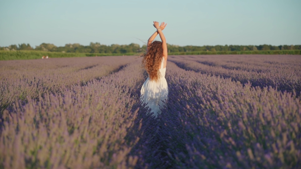 Woman walks from behind among the lavender plants