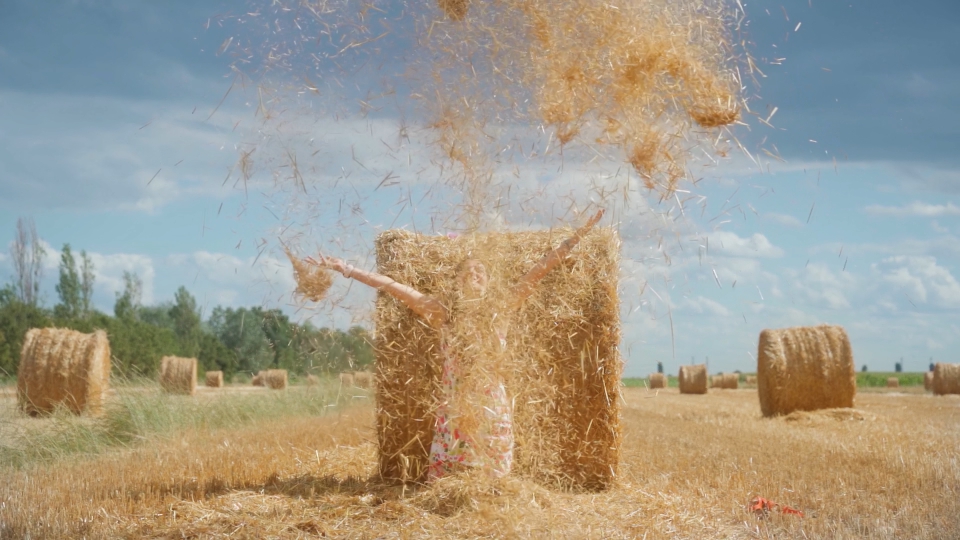 Ripresa reverse del fieno che si alza nel cielo sul campo agricolo