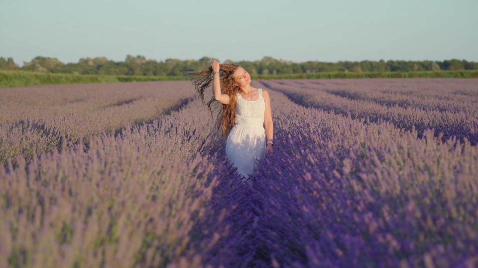 Ragazza felice e sorridente cammina tra le file di lavanda