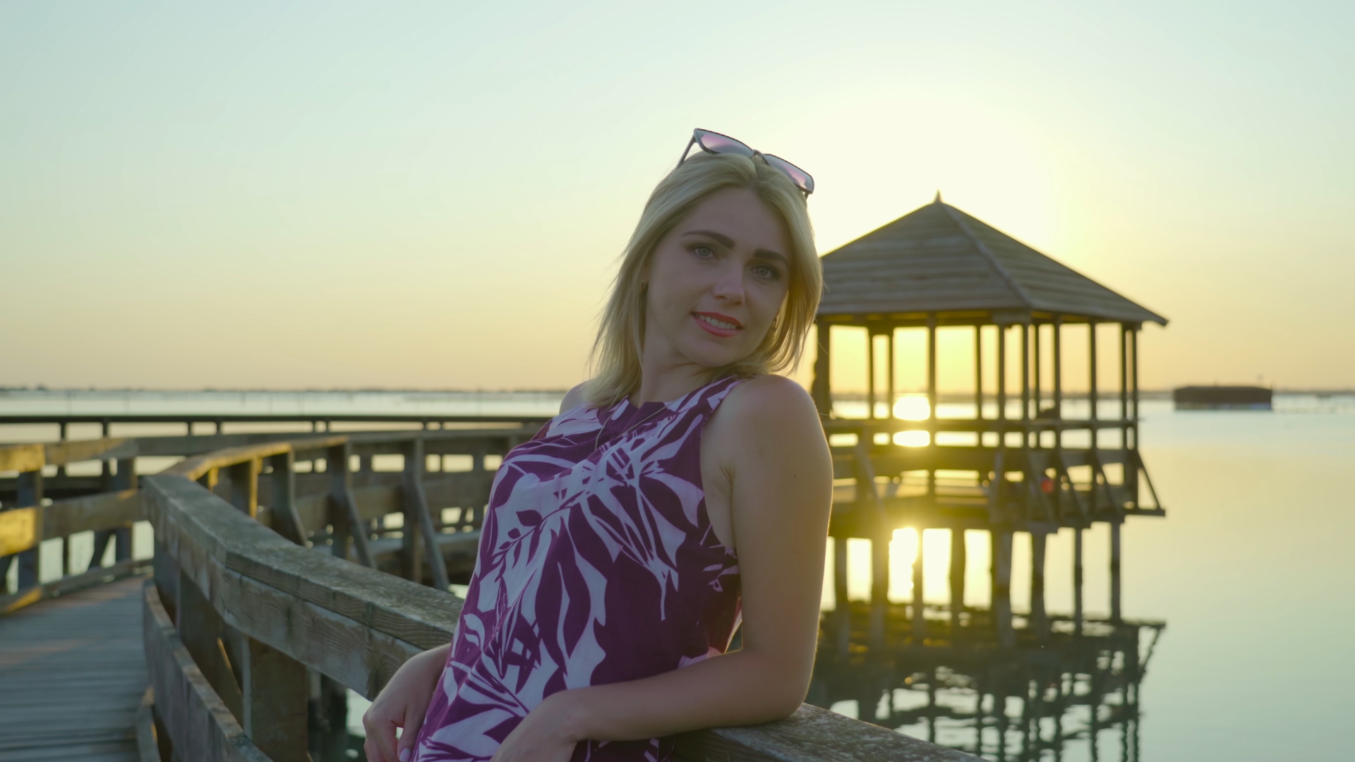 Blond woman smiles looking into camera at sunset