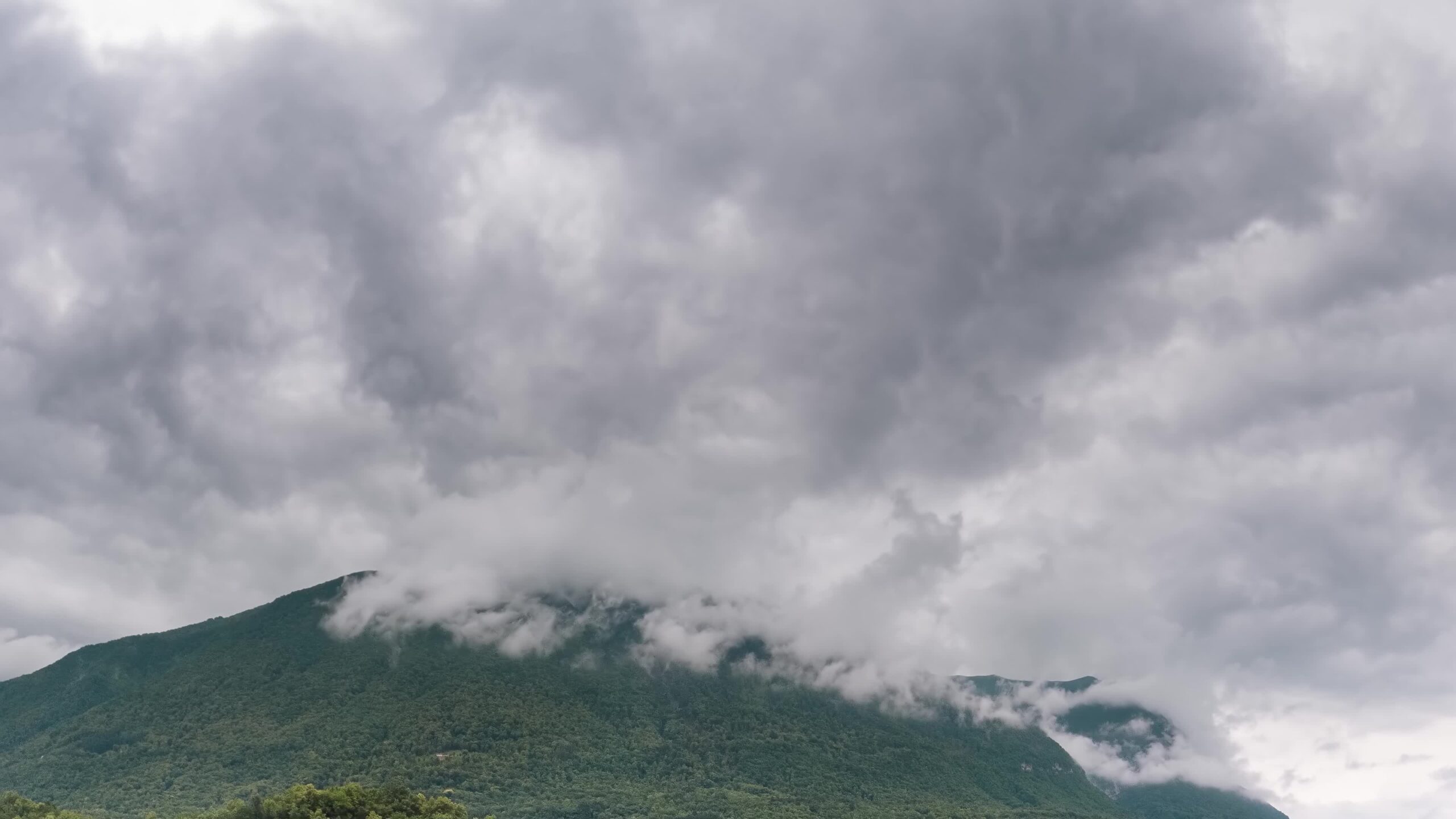 Cielo nuvoloso scorre velocemente sopra montagna verde