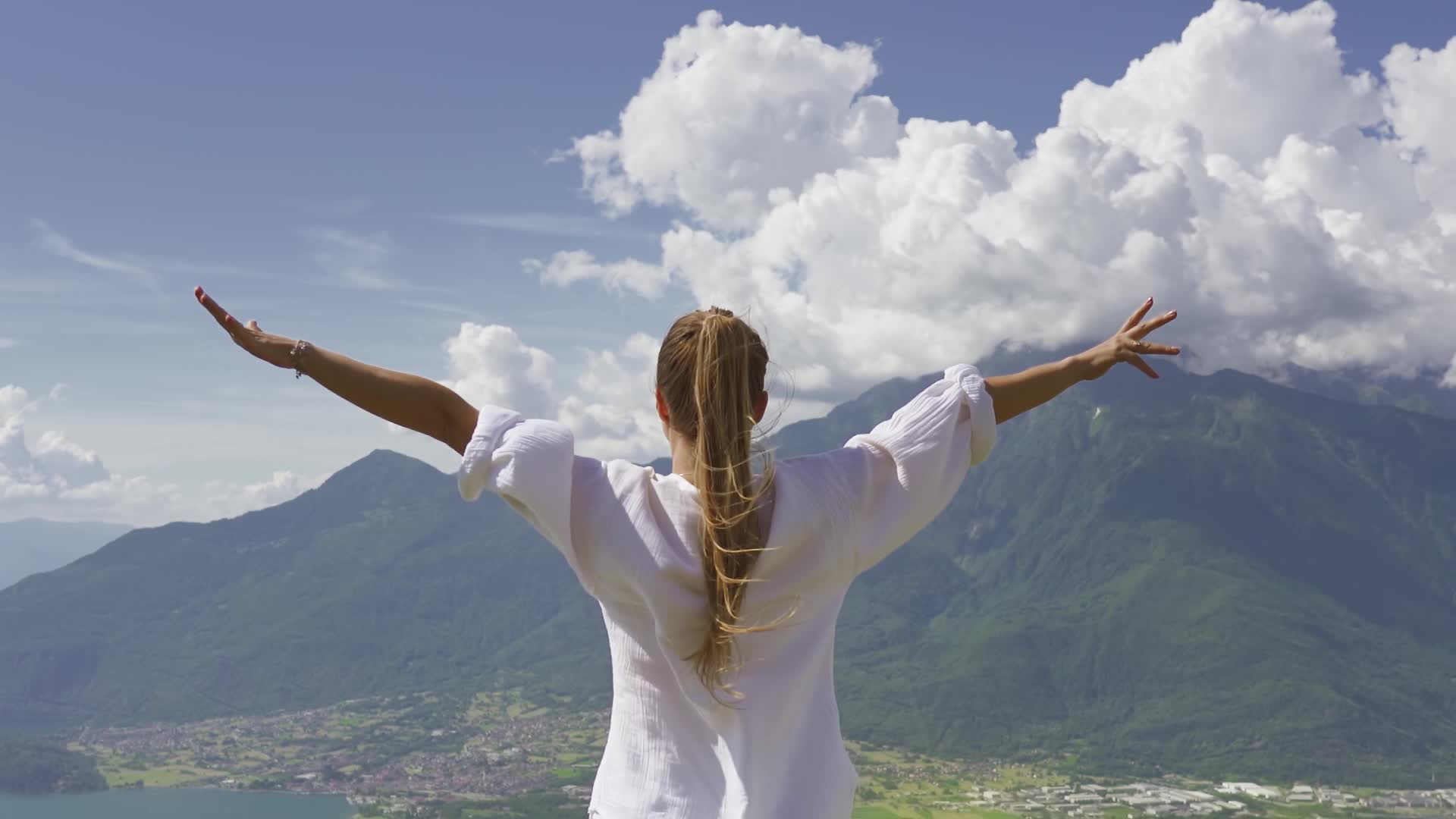 Woman raises her arms in the mountains