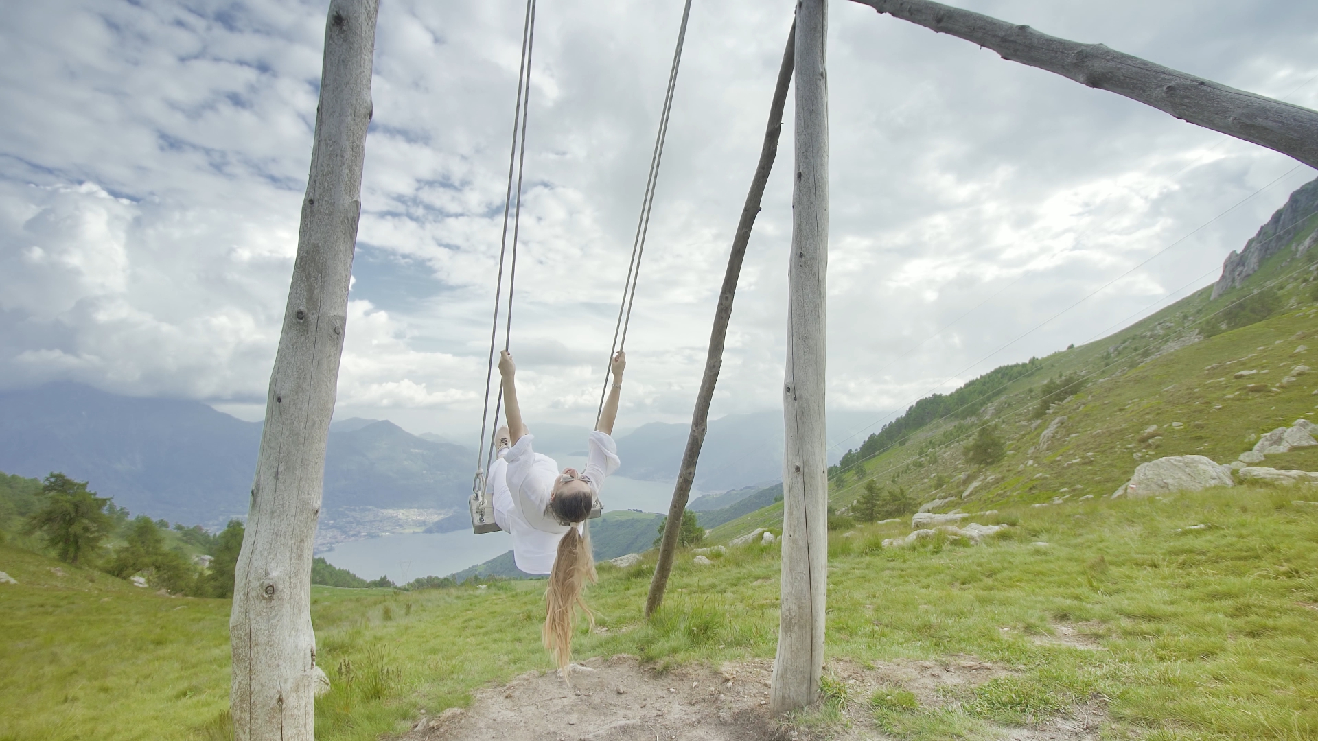 Person swings on a swing above the mountains