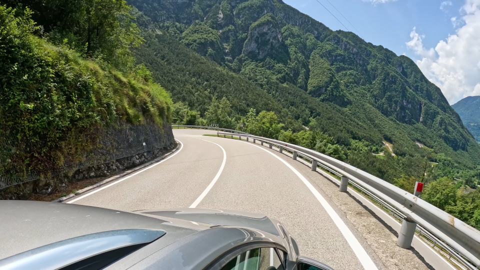 Time-lapse of the car on the road between mountains with green woods in summer