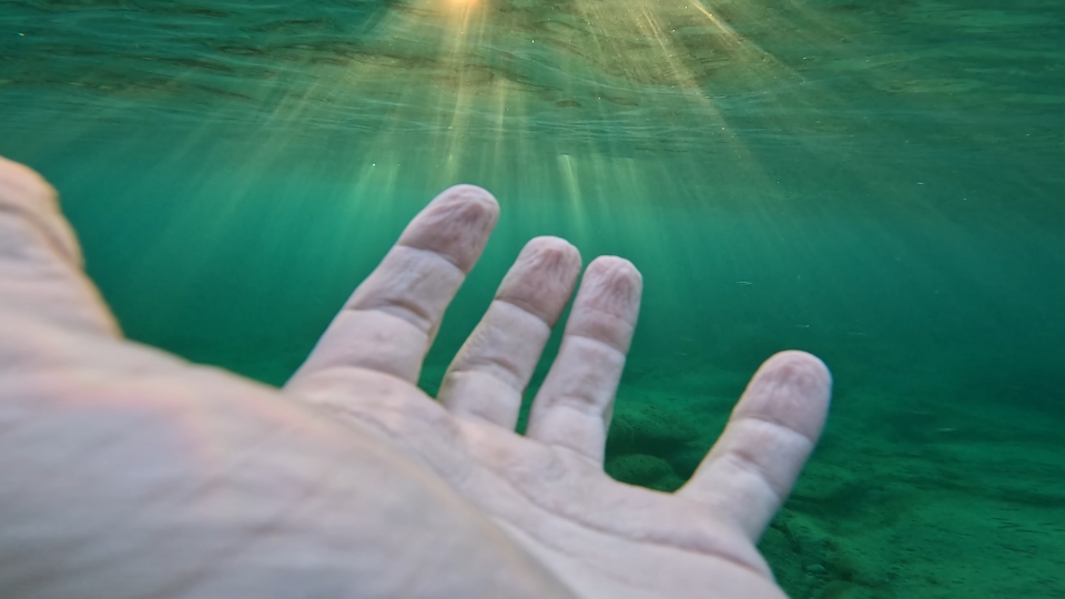 Mano davanti raggi di luce sott’acqua