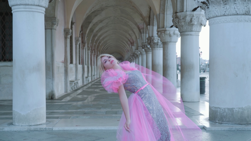 Woman in elegant pink dress in front of Venetian arches