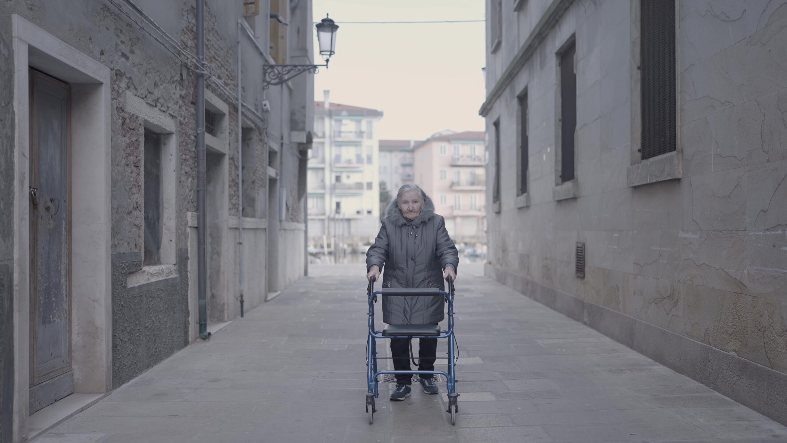 Donna anziana con deambulatore percorre le strade urbane