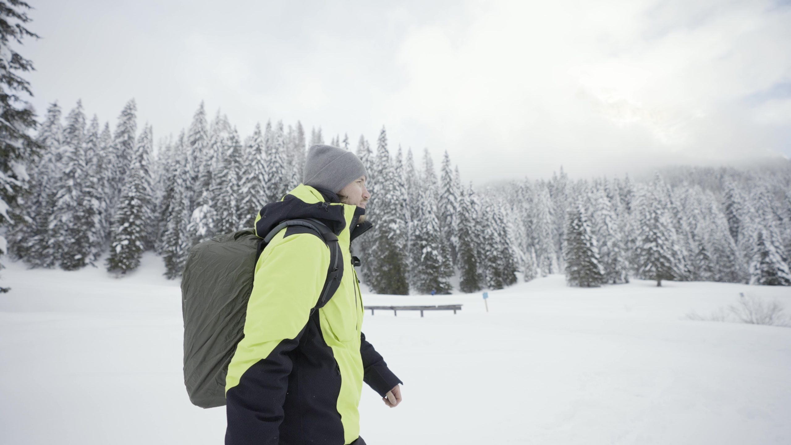 Man with backpack walks in the snow near the forest