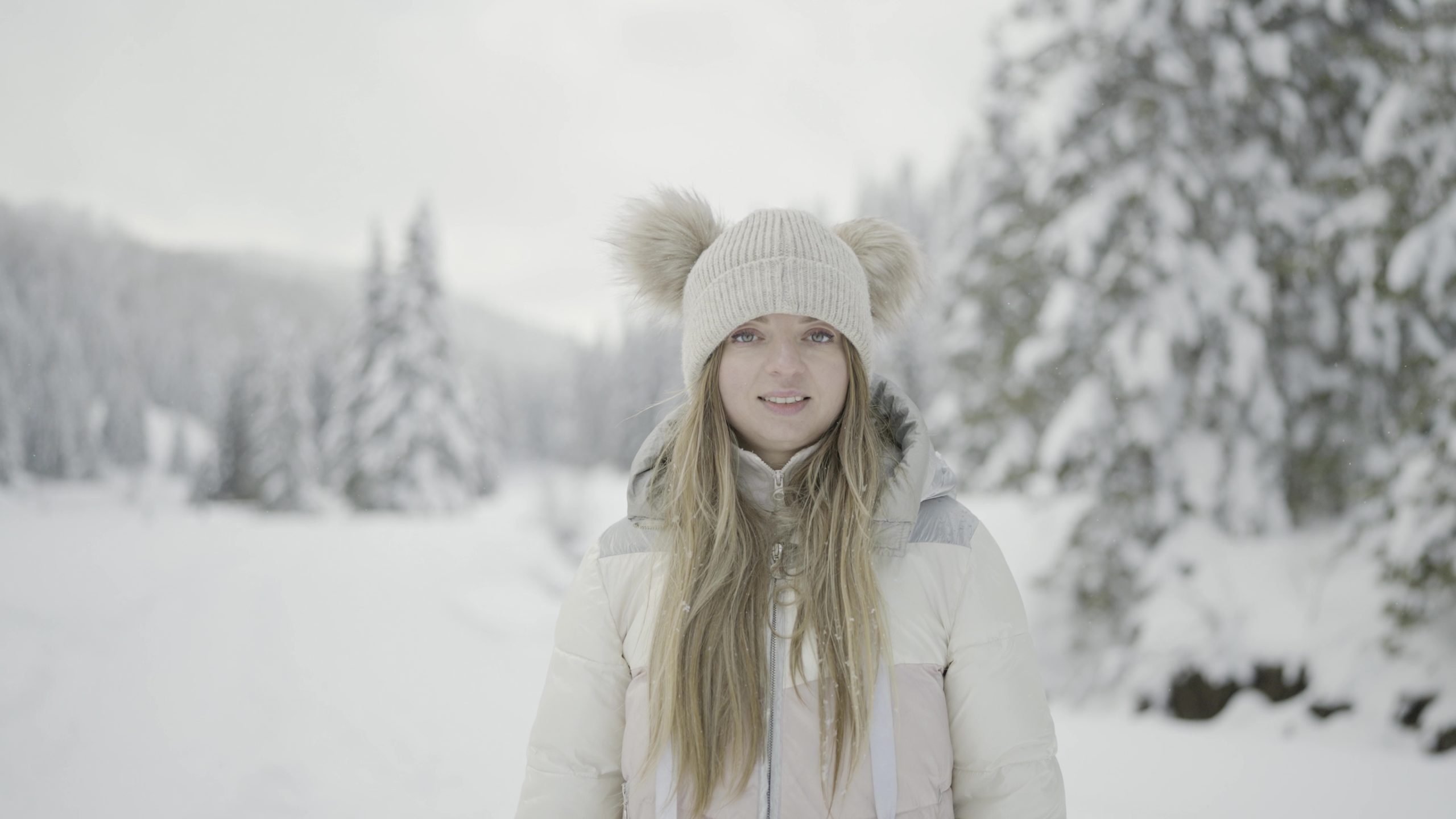 Viso della donna che sorride ferma in inverno tra alberi del bosco