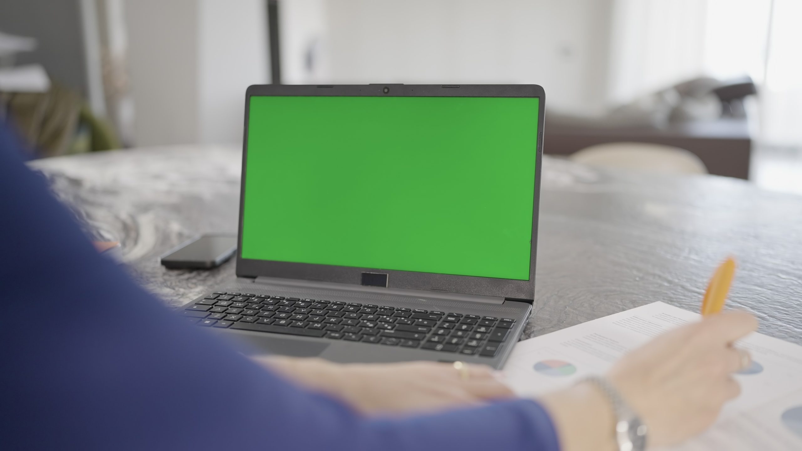 Woman works near computer with green screen