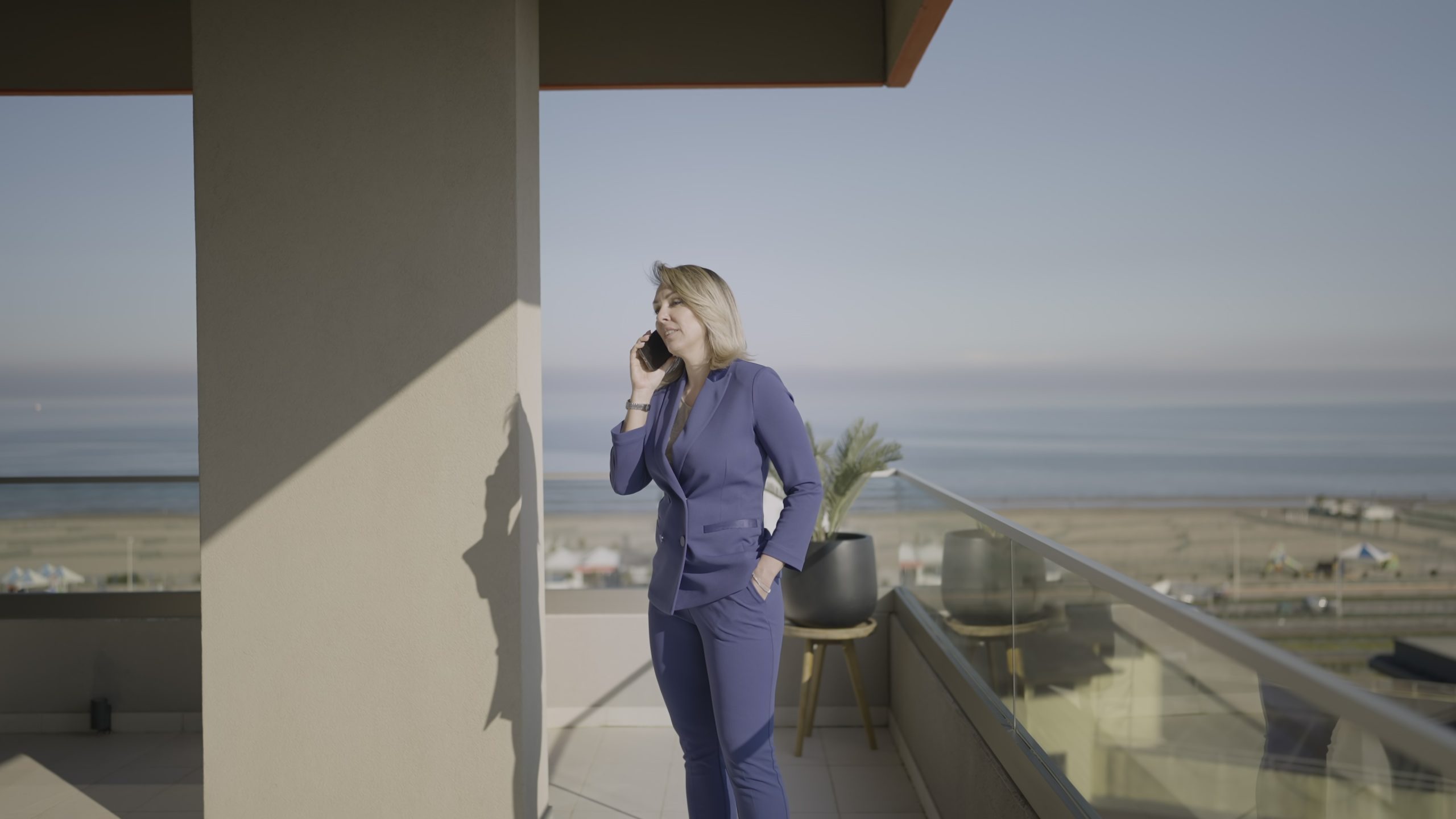 Donna parla al telefono sul poggiolo con vista mare