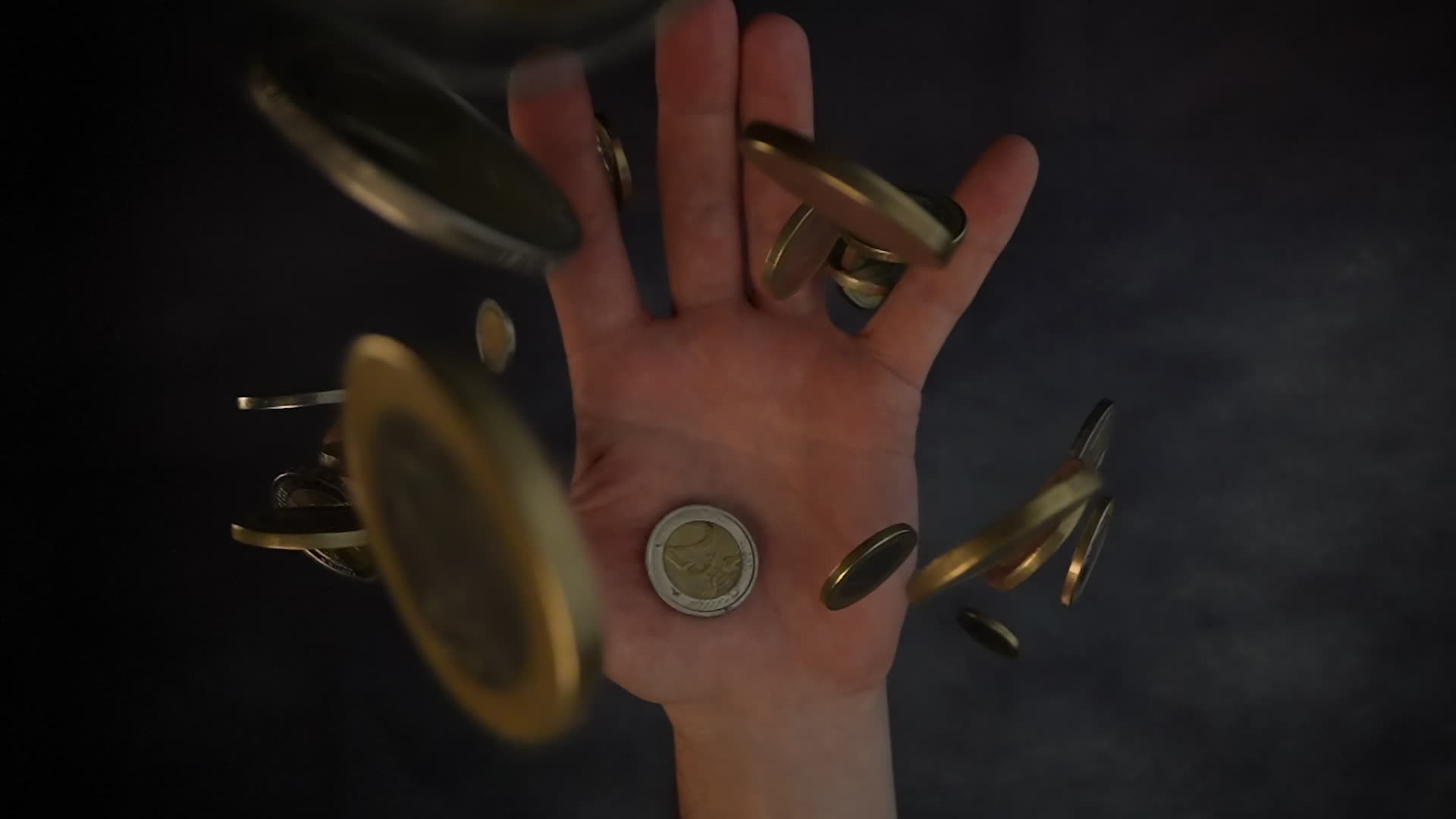 Golden coins fall in slow motion into man’s hand