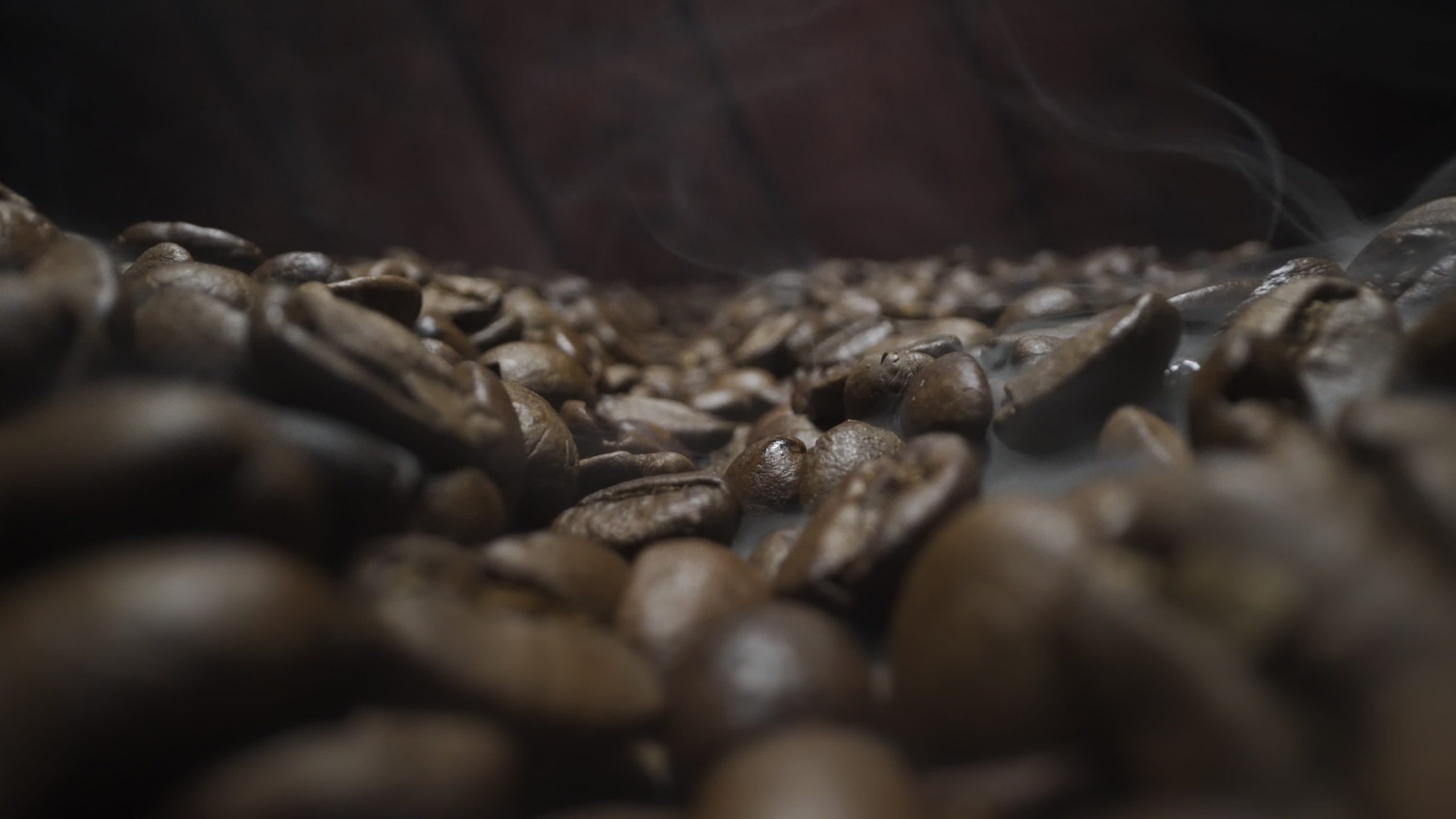 Chicchi di caffè tostati scuri con fumo che sale