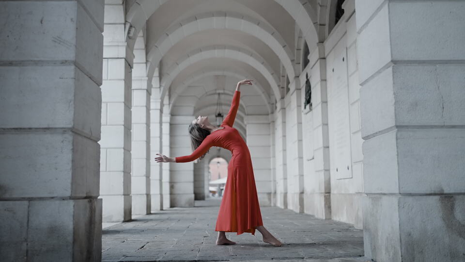 Graceful dancer in red dress under stone archways