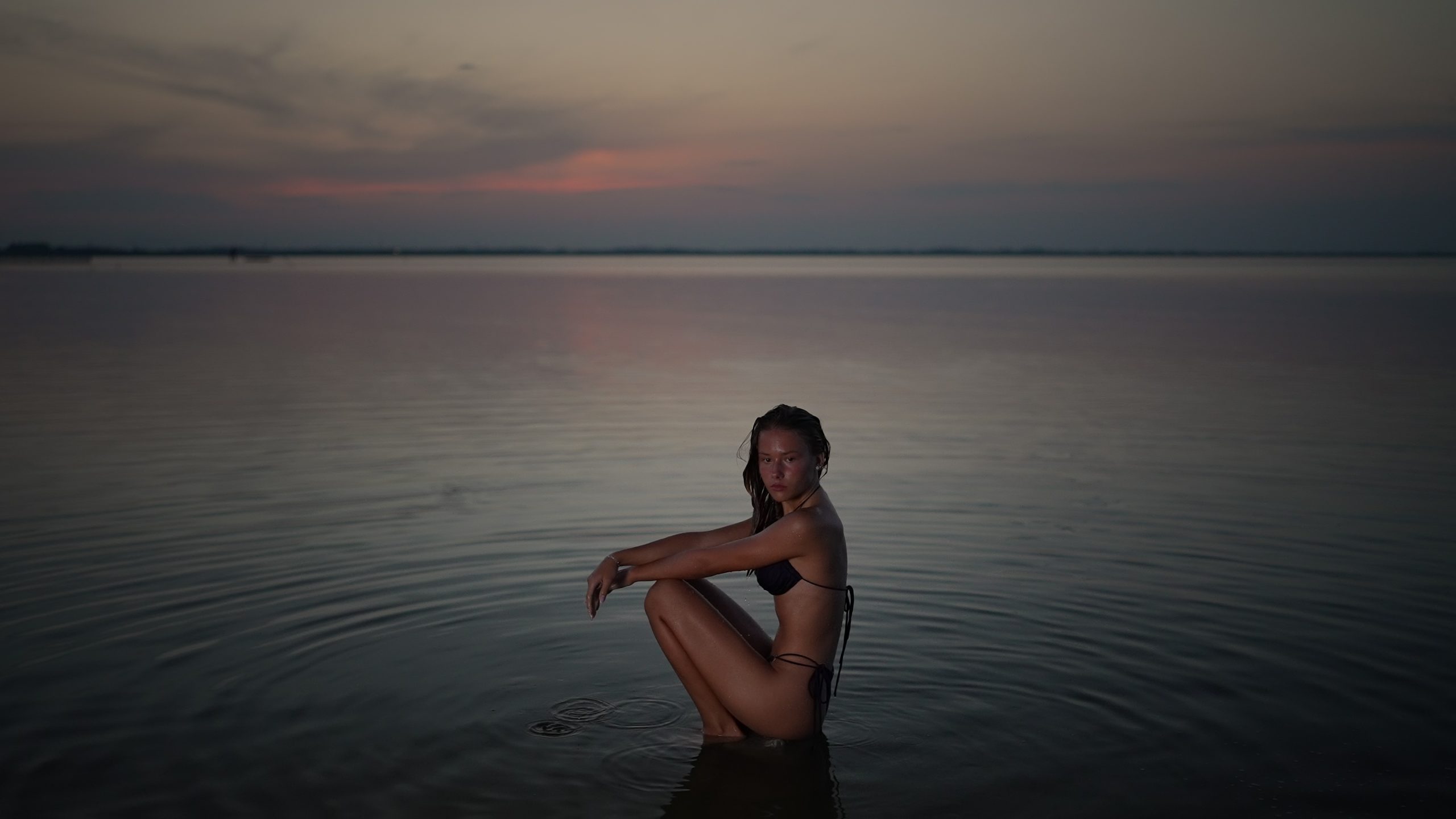 Donna Seduta nell’Acqua Calma al Crepuscolo